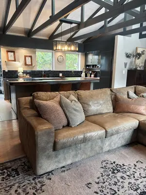 a brown couch in a living room with a kitchen at Pool & Garden Winelands Retreat in Stellenbosch