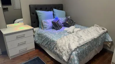 a bedroom with a bed with a dresser and a night stand at Cozy Corner Guest House 25 Harpford avenue wynberg CAPE TOWN WESTERN CAPE in Cape Town