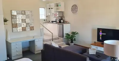 a living room with a couch and a desk at Cozy studio flat in Goodwood in Goodwood