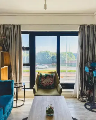 a living room with a couch and a large window at Shiloh Apartment on Burmeister in Cape Town