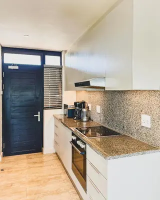 a kitchen with white cabinets and a black door at Shiloh Apartment on Burmeister in Cape Town