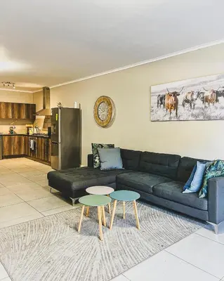a living room with a black couch and two tables at Spacious 2 bedroom Apt near Canal Walk in Cape Town
