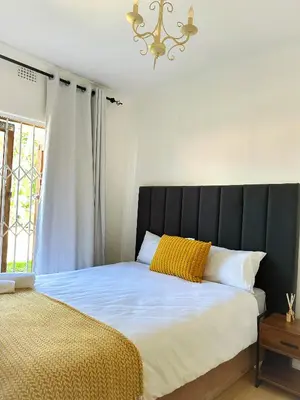 a bed with a black headboard next to a window at Lux Sleek City Haven in Cape Town