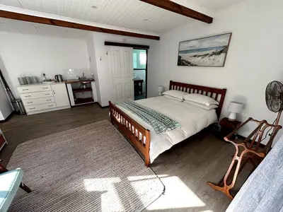 a bedroom with a bed and a table and a desk at Protea Escape - sea, sand and sun on your doorstep in Hermanus