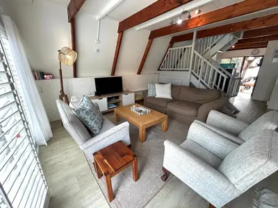 a living room with couches and a tv and a table at Protea Escape - sea, sand and sun on your doorstep in Hermanus