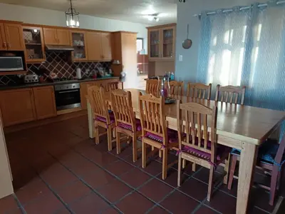 a kitchen with a wooden table and wooden chairs at Beautifully Sea View Escape Vermont 5 bedrooms in Hermanus