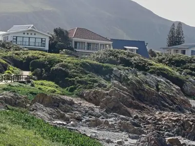 a house on top of a hill next to a river at Beautifully Sea View Escape Vermont 5 bedrooms in Hermanus