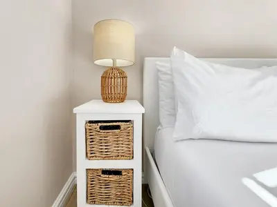 a lamp on a night stand next to a bed at Tranquil Garden Cottage in Cape Town