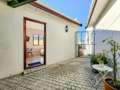 an open door to a patio with a table at Tranquil Garden Cottage in Cape Town