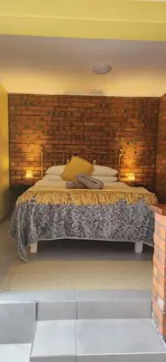 a bedroom with a large bed in a brick wall at LyonsDen 1 in Worcester