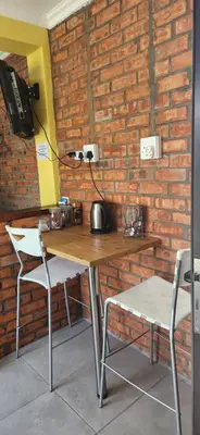 a table with two chairs and a lamp on a brick wall at LyonsDen 1 in Worcester