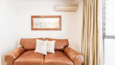 a brown leather couch with two white pillows on it at The Mustard Seed in Stellenbosch