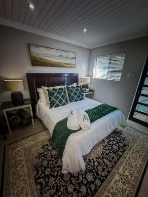 a bedroom with a large bed with two towels on it at Ziminé Cottage in Paarl