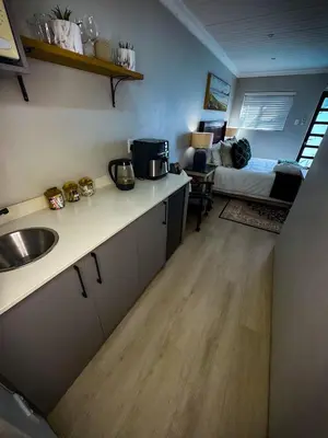a kitchen with a sink and a living room at Ziminé Cottage in Paarl