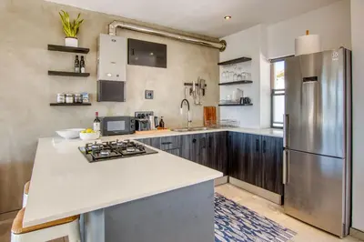 a kitchen with a refrigerator and a counter top at Ocean & Mountain View Escape, 100m Walk to beach - Gordon's Bay in Gordonʼs Bay