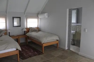 a bedroom with two beds and a bathroom with a sink at Stellenbosch family villa in Stellenbosch
