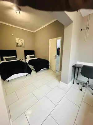 a room with two beds and a desk in it at AAA Luxury Homes in Cape Town