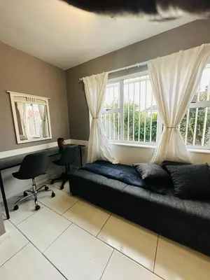 a bedroom with a bed and a desk and a window at AAA Luxury Homes in Cape Town