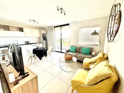 a living room with a couch and a tv and a kitchen at Luxe Waters Edge apt next to Canal Walk in Cape Town