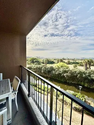 a balcony with a table and a view of a river at Luxe Waters Edge apt next to Canal Walk in Cape Town