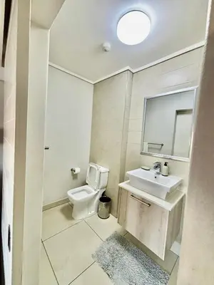a bathroom with a toilet and a sink and a mirror at Luxe Waters Edge apt next to Canal Walk in Cape Town