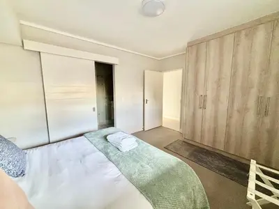 a bedroom with a large bed and wooden cabinets at Luxe Waters Edge apt next to Canal Walk in Cape Town