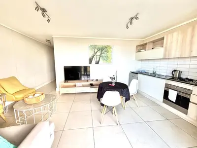 a kitchen and living room with a table and chairs at Luxe Waters Edge apt next to Canal Walk in Cape Town