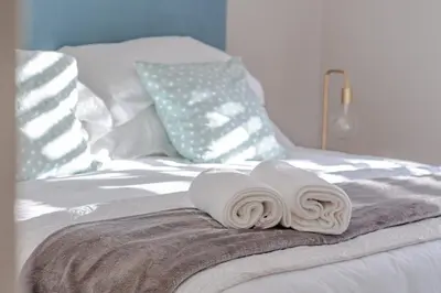 a bed with two white towels on top of it at Belle Apartment in Hermanus