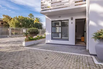 a white house with a window and a fence at Belle Apartment in Hermanus