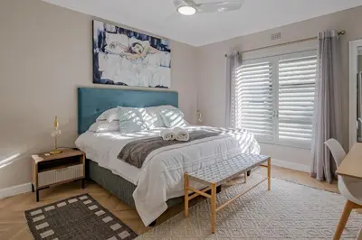 a bedroom with a bed with a teddy bear on it at Belle Apartment in Hermanus