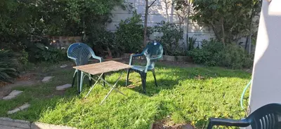 two chairs and a table in the grass at Clay Stone Cottage in Goodwood