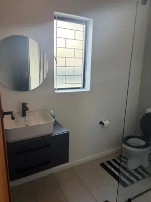 a bathroom with a sink and a toilet and a mirror at TLP Haven in Cape Town