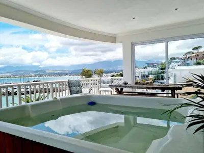a bath tub in a balcony with a view of the water at Penthouse on the beach, Jacuzzi with 3 bedrooms in Cape Town