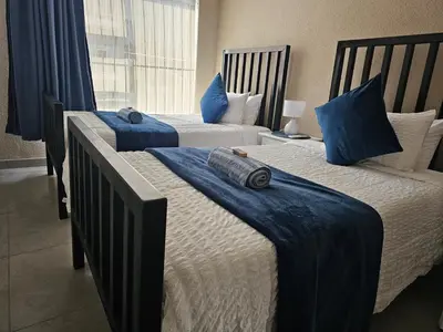 two beds in a bedroom with blue sheets and pillows at Evert's Home in Bellville