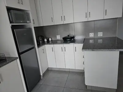a kitchen with white cabinets and a black refrigerator at Evert's Home in Bellville