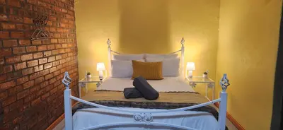 a bedroom with a bed with two lamps and a brick wall at LyonsDen 2 in Worcester