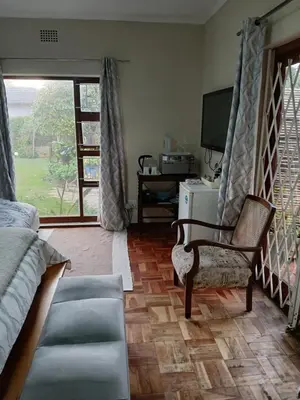 a bedroom with a couch and a chair and a television at Rusticana A in Cape Town