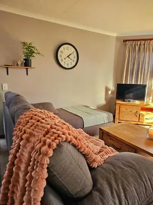 a living room with a couch and a clock on the wall at Max 7 in Helderberg