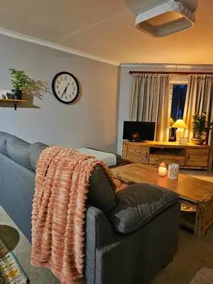 a living room with a couch and a clock on the wall at Max 7 in Helderberg