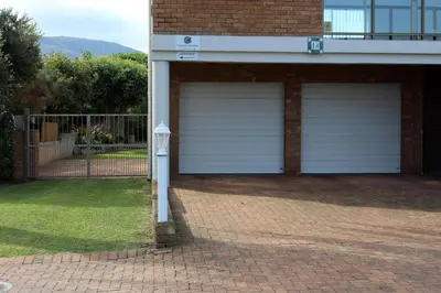 a garage with two white garage doors on a house at Grace Haven Self Catering in Hermanus