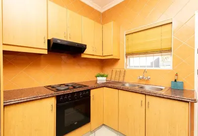 a kitchen with wooden cabinets and a sink and a stove at Serena Inn Apartment 6 Self Catering in Cape Town