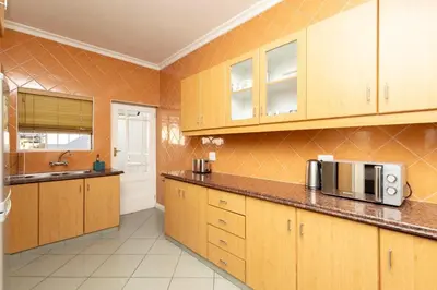 a kitchen with wooden cabinets and a microwave at Serena Inn Apartment 6 Self Catering in Cape Town