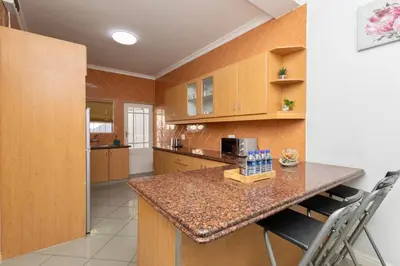 a kitchen with a counter with chairs and a microwave at Serena Inn Apartment 6 Self Catering in Cape Town
