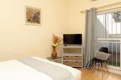 a bedroom with a bed and a tv and a chair at Serena Inn Apartment 6 Self Catering in Cape Town