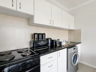 a kitchen with a stove and a washing machine at Rivers Edge Apartment in Rondebosch with Balcony in Cape Town