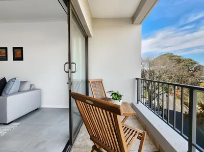 a balcony with a chair and a couch at Rivers Edge Apartment in Rondebosch with Balcony in Cape Town