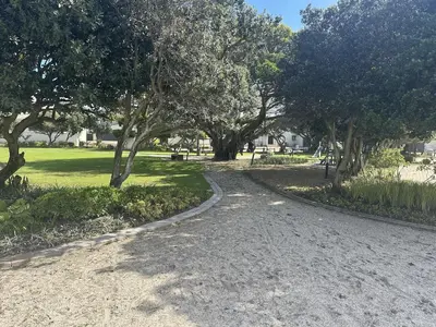 a dirt road in a park with trees and grass at Sunset Links Golf Estate home, walk to Beach in Cape Town