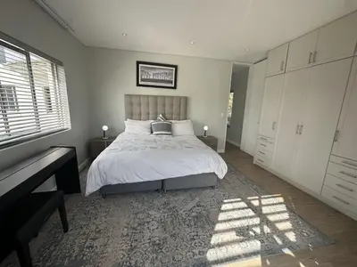 a bedroom with a bed and a desk and a window at Sunset Links Golf Estate home, walk to Beach in Cape Town