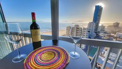 a table with a bottle of wine and two wine glasses at Views Views and more Views Stunning 2 bed Apartment in Strand