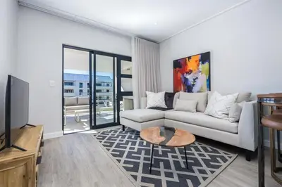 a living room with a couch and a tv at Esplanade Hermanus Central Sea Views in Hermanus